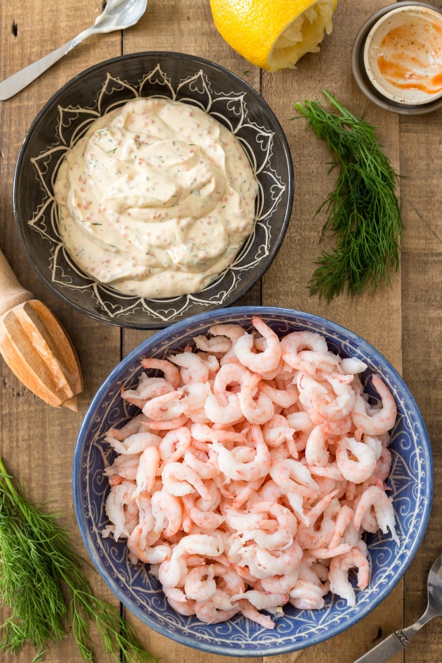 Bowl of creamy base for shrimp salad and bowl with shrimps.