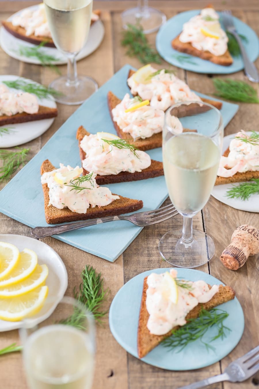Skagenröra shrimp salad on rye toast, glasses of prosecco around.