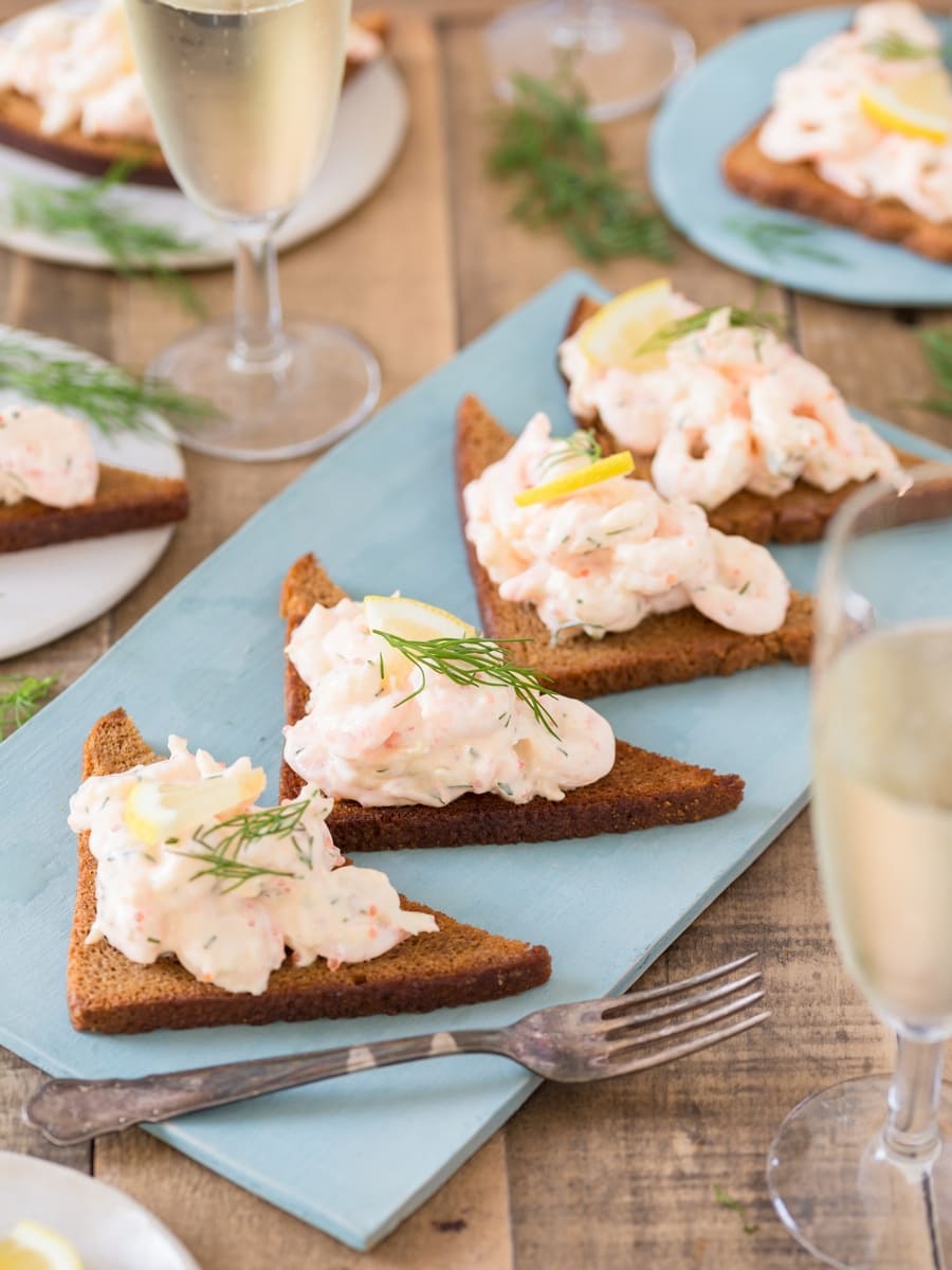 Rye toast with shrimp salad skagenröra on a blue plate.
