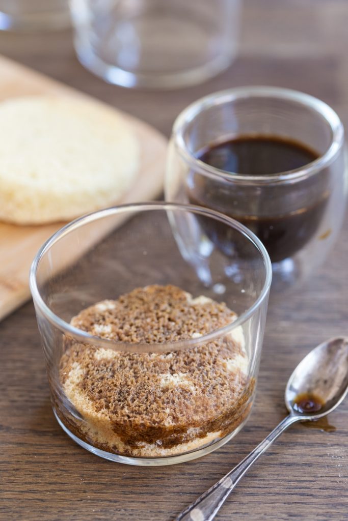 Tiramisu in a glass preparation: soaking the sponge cake with sweetened coffee.