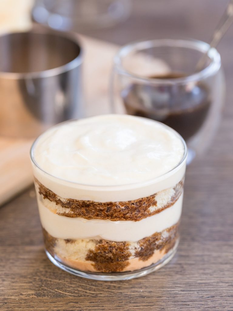 Making tiramisu in a glass: the final layer of cream is added.