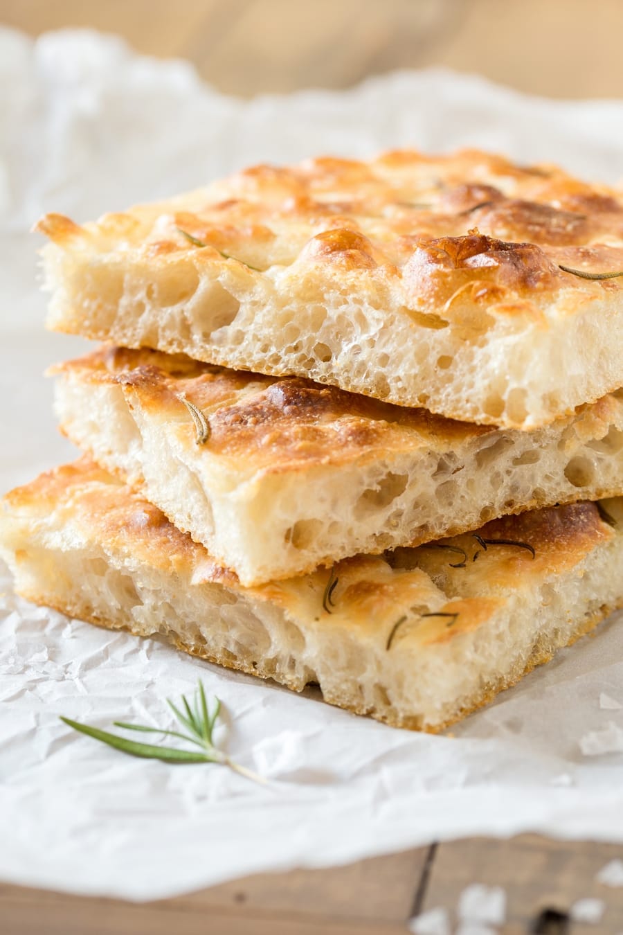 Slices of focaccia, stacked on white paper.