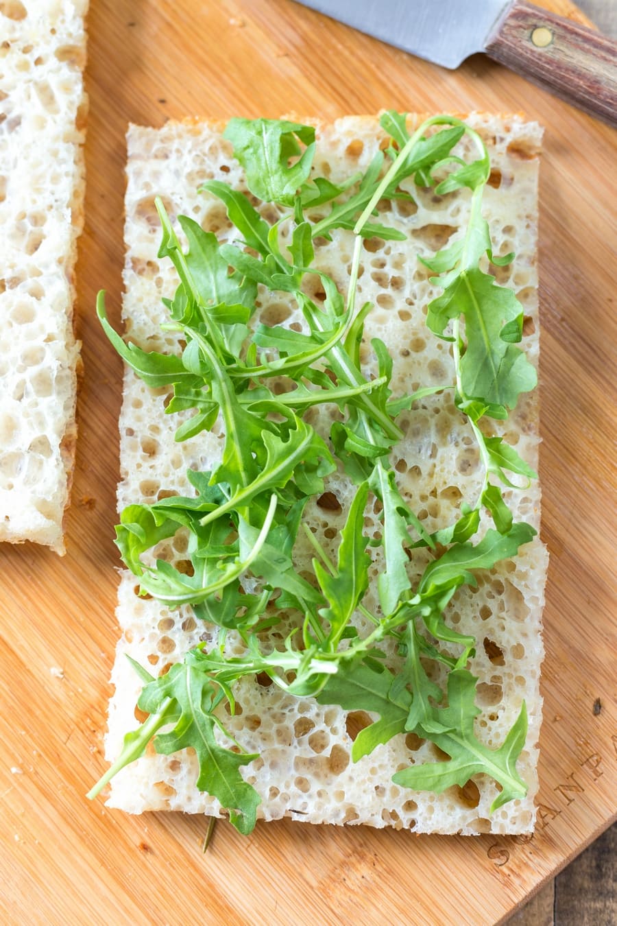 Fresh rocket leaves on sliced focaccia bread.