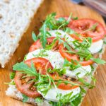 Tomato mozzarella sandwich on focaccia bread. Caprese sandwich with rocket leaves.