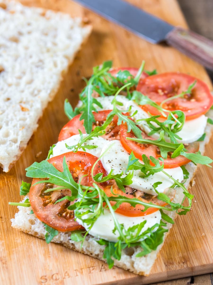 Tomato mozzarella sandwich on focaccia bread. Caprese sandwich with rocket leaves.