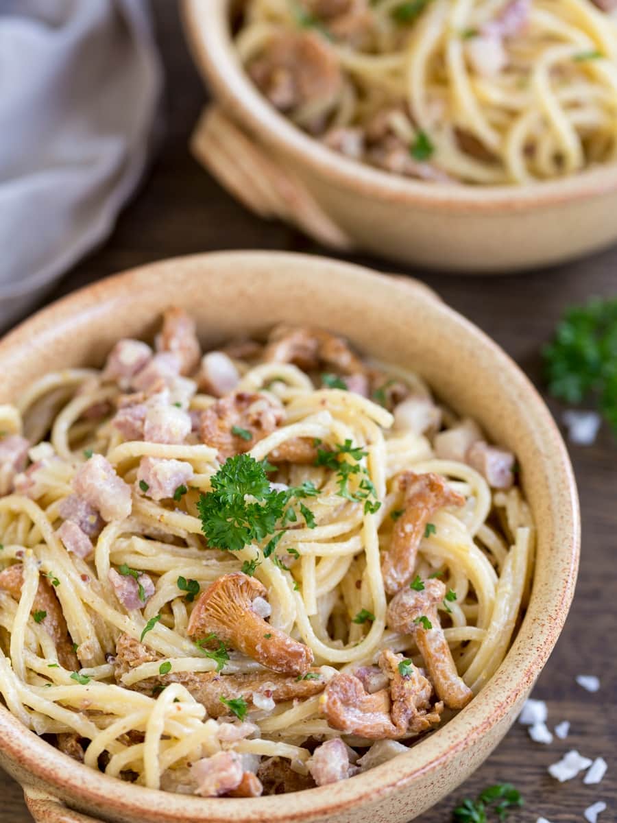 Bowl of honey mustard pasta with mushrooms and bacon.