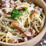 Closeup of creamy mustard pasta with bacon and chanterelles.
