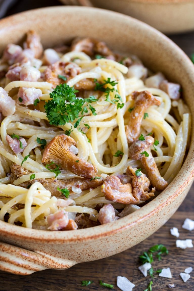 Closeup of creamy mustard pasta with bacon and chanterelles.