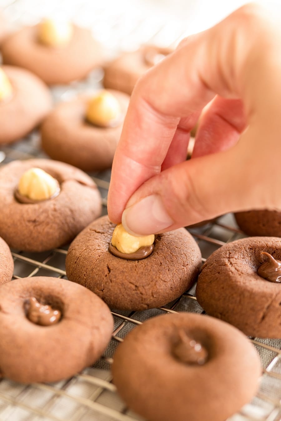 Pressing a whole hazelnut into the nutella filling of nutellotti cookies.