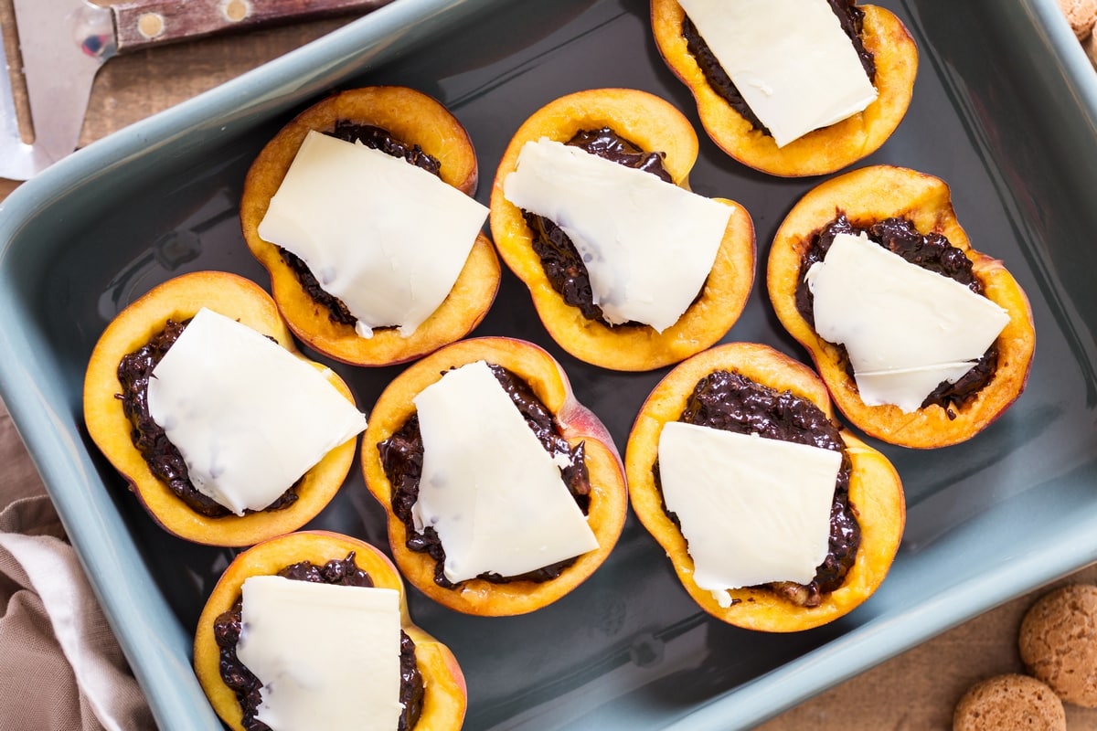 Adding butter to filled peaches to make amaretti stuffed peaches.