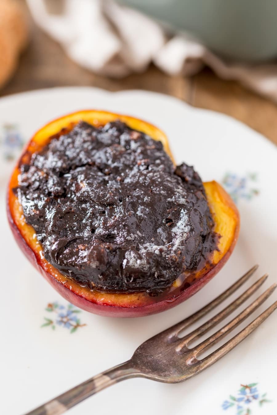 Baked peach with amaretti stuffing on a plate.
