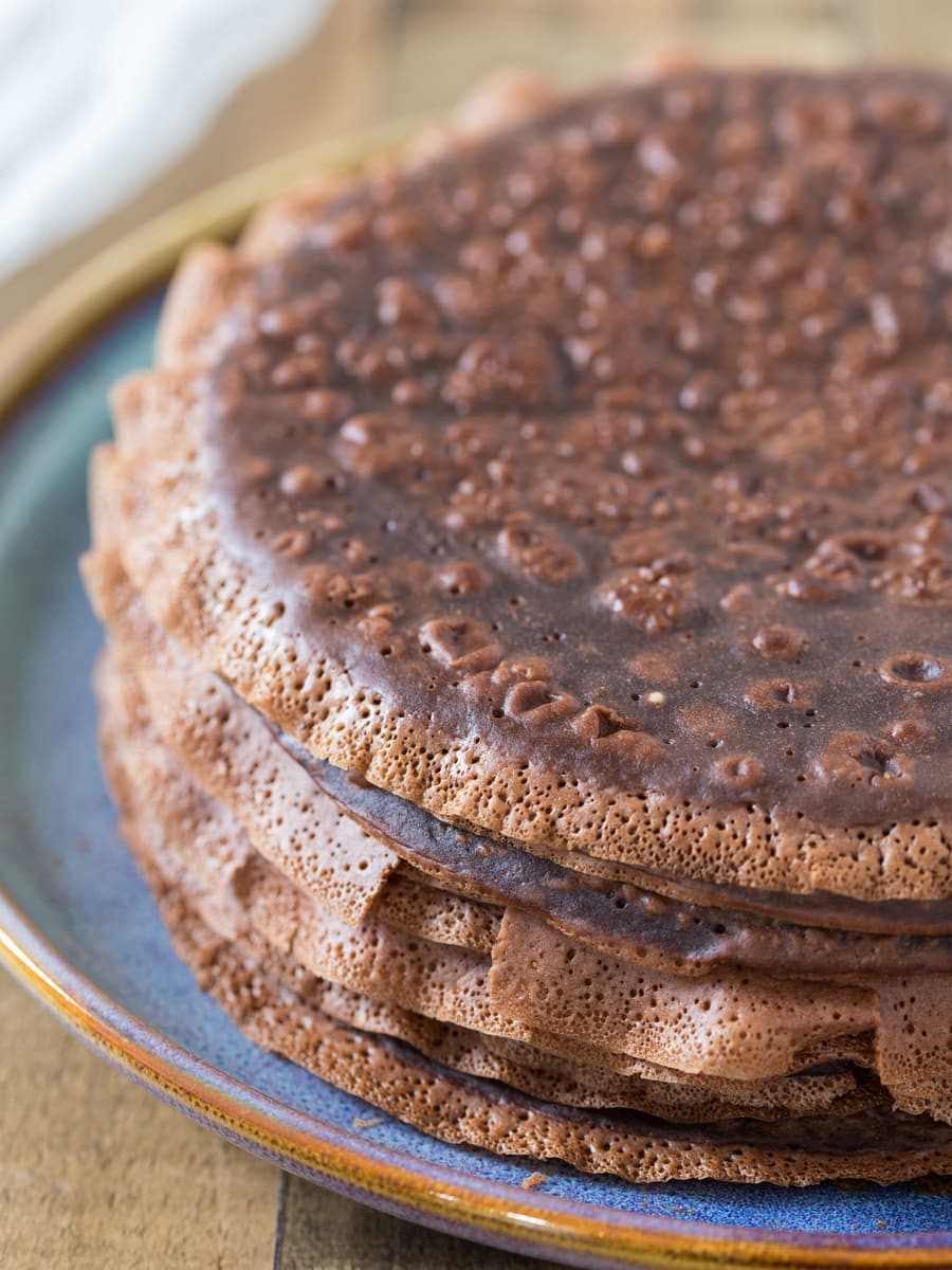 Chocolate crepes stacked on a plate.
