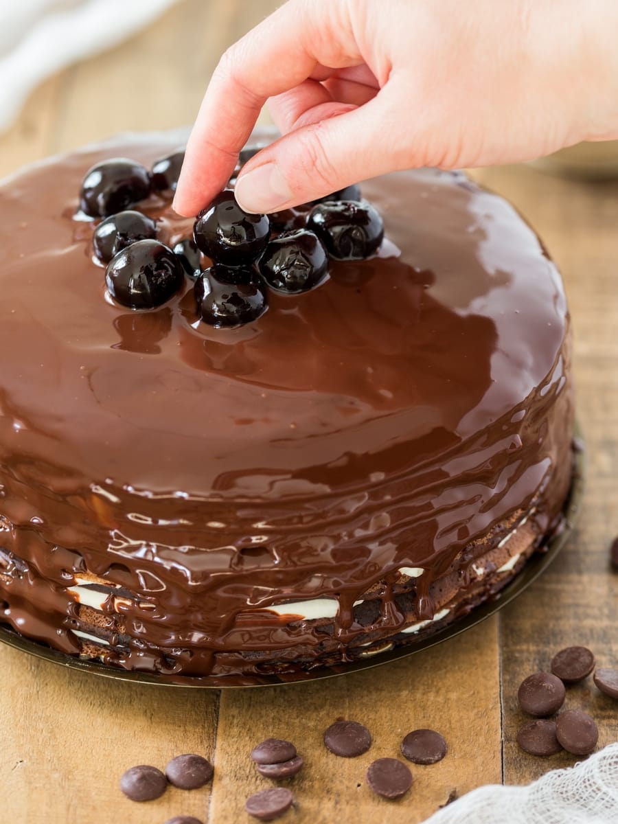 Adding sour cherries on top of black forest crepe cake.