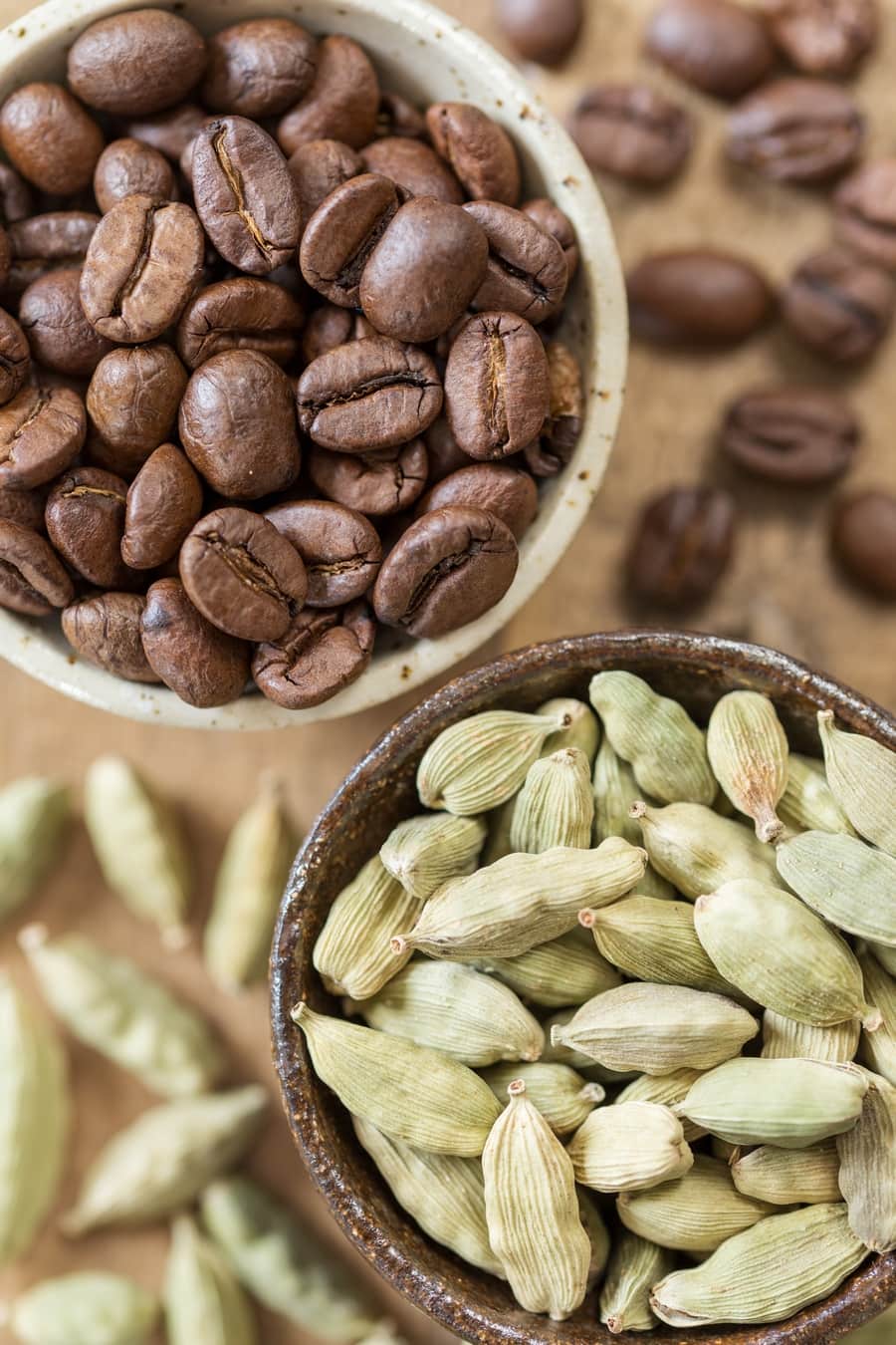 Coffee beans and cardamom pods in small bowls.