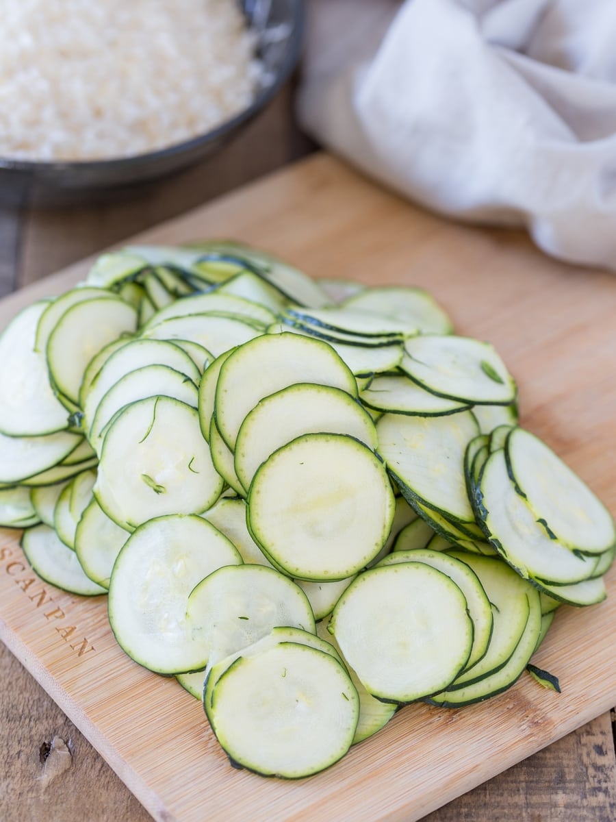 Thinly sliced zucchini on a cutting board.