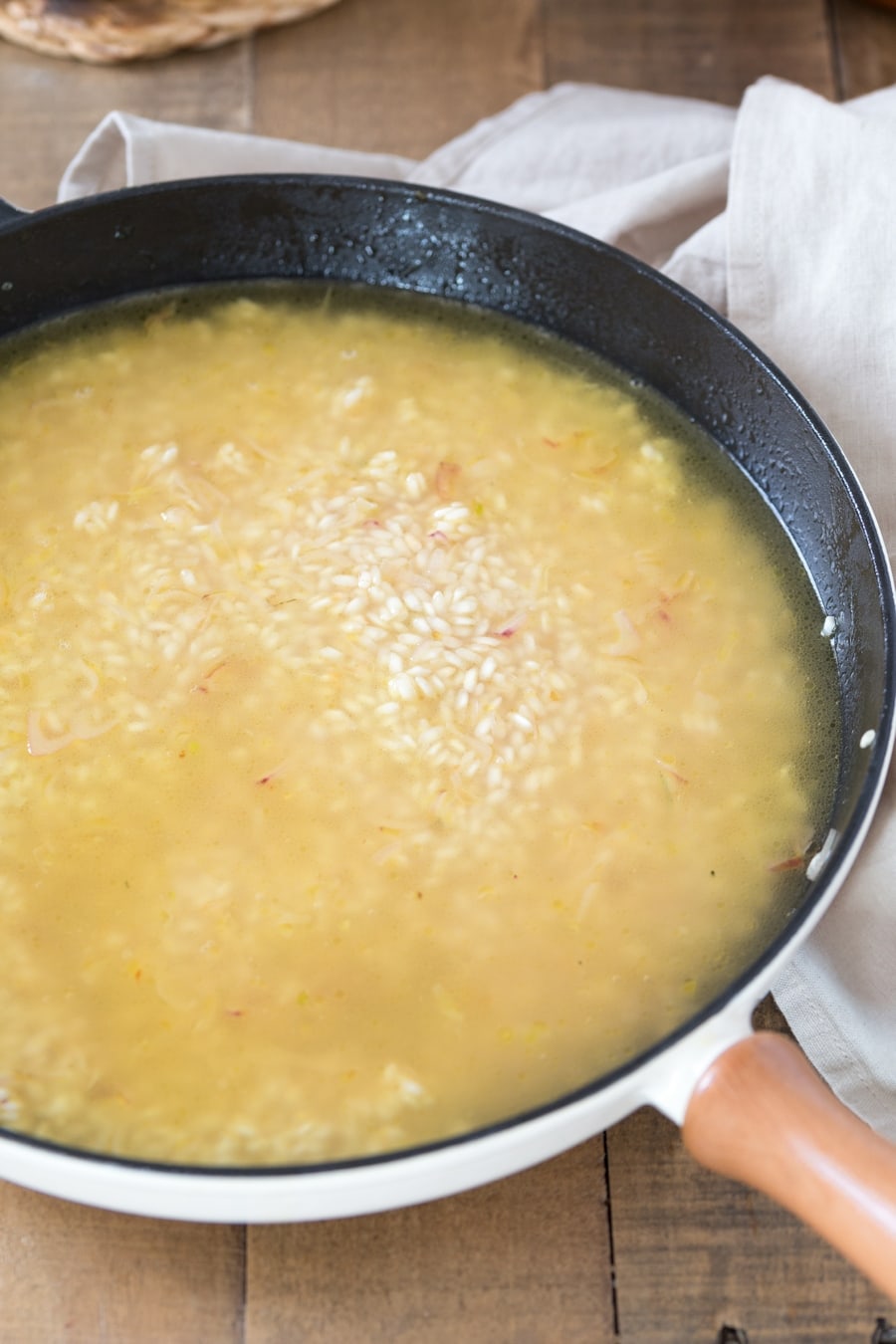 Zucchini cheddar risotto preparation: vegetable stock added to rice.