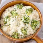 Zucchini cheddar risotto in a brown serving dish.