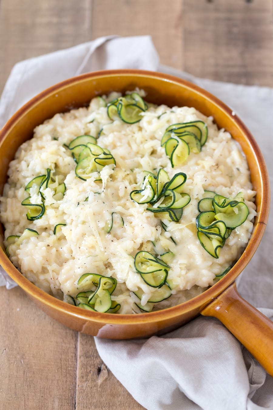 Zucchini cheddar risotto in a brown serving dish.