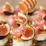 Drizzling honey over baked chevre with figs and prosciutto.