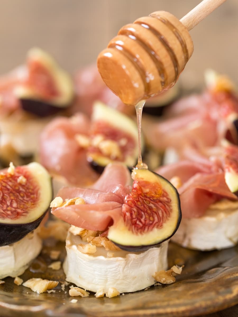 Drizzling honey over baked chevre with figs and prosciutto.