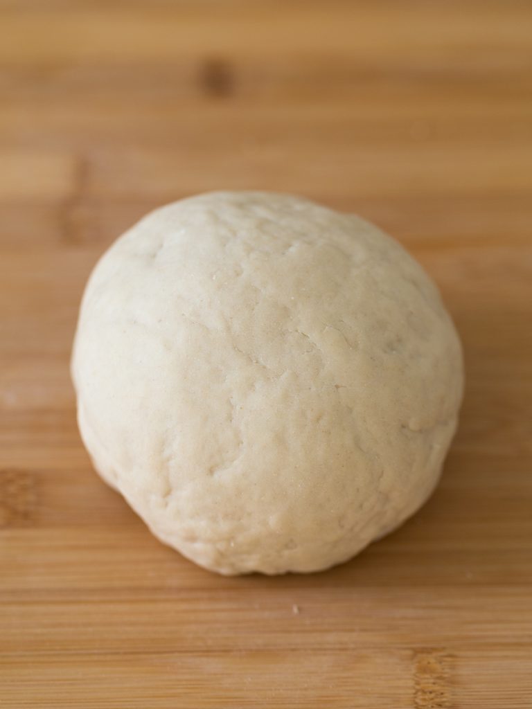 Ball of pierogi dough on wooden surface.