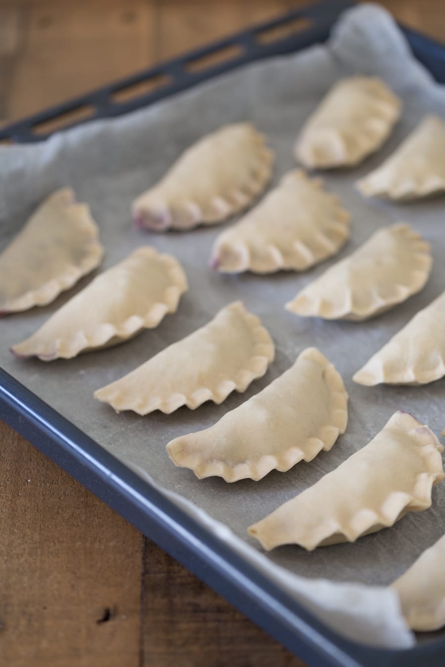 Uncooked pierogi on a tray.