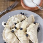 Cooked blueberry pierogi served with sour cream.