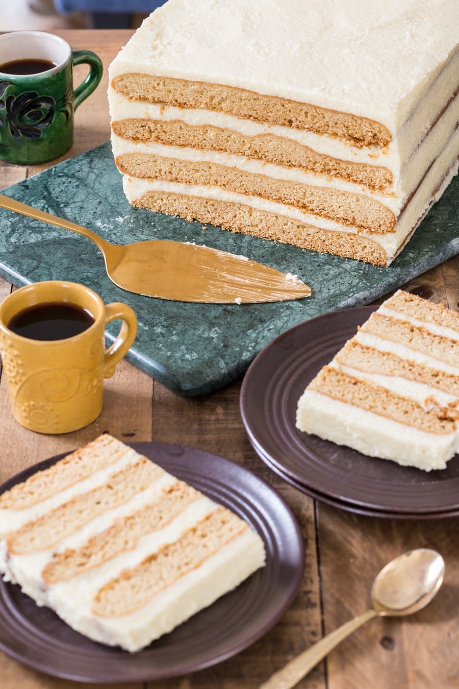 Honey cake served on green marble tray, slices on brown plates.
