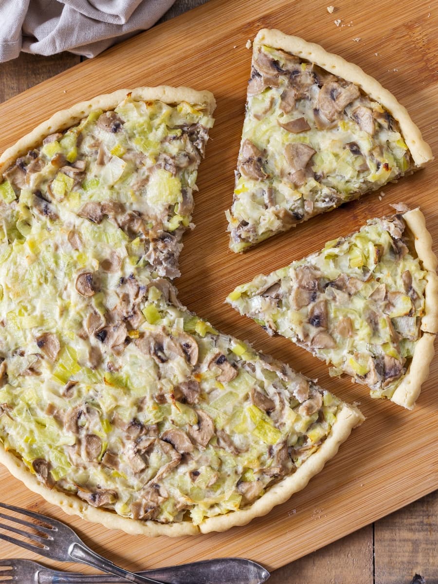 Mushroom leek pie sliced on a wooden cutting board.