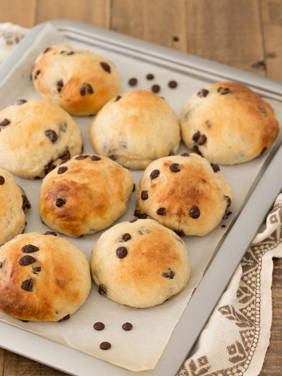 Norwegian cardamom rolls with chocolate chips on a baking tray.