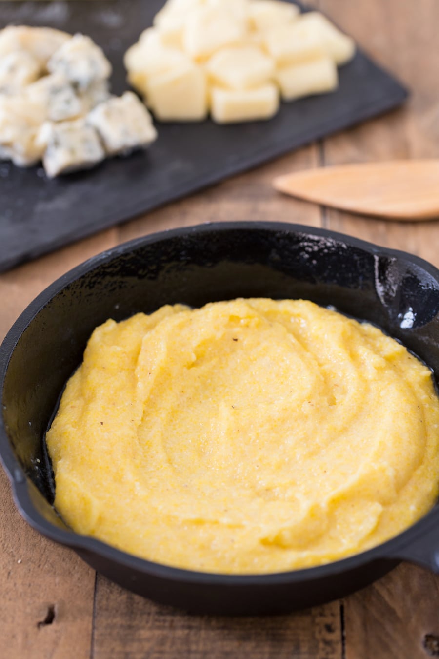 Polenta concia preparation: adding polenta to an oven safe dish.