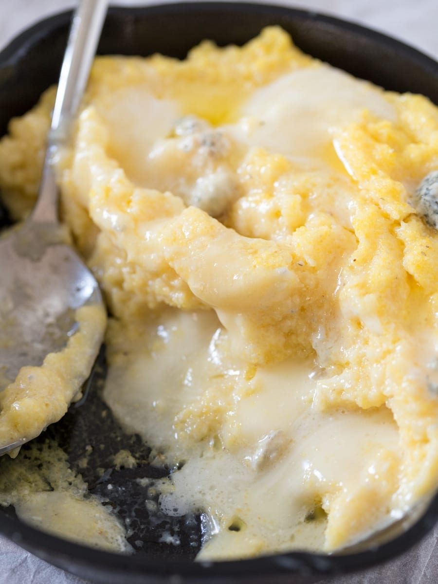 Scooping through a serving of polenta concia, melted cheese pouring out.