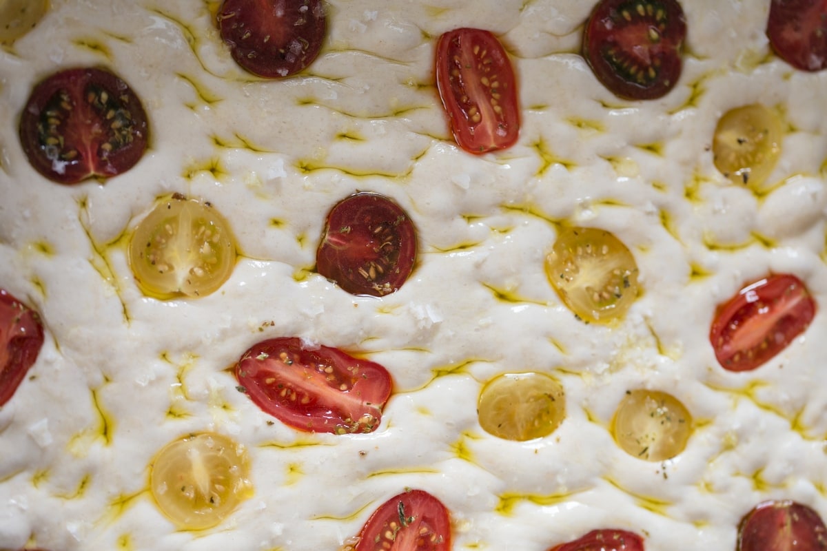 Seasoned halved cherry tomatoes pressed onto focaccia surface.