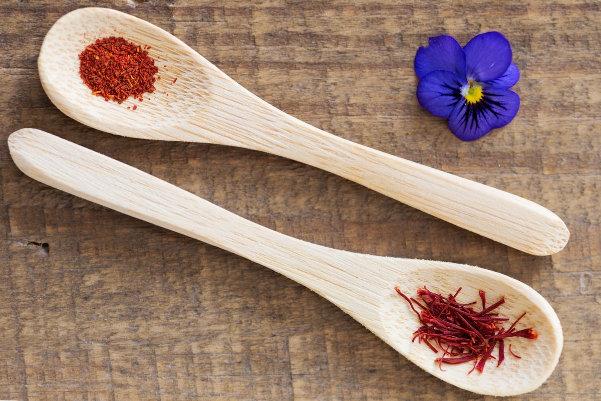 Two small wooden spoons with saffron threads and ground saffron.