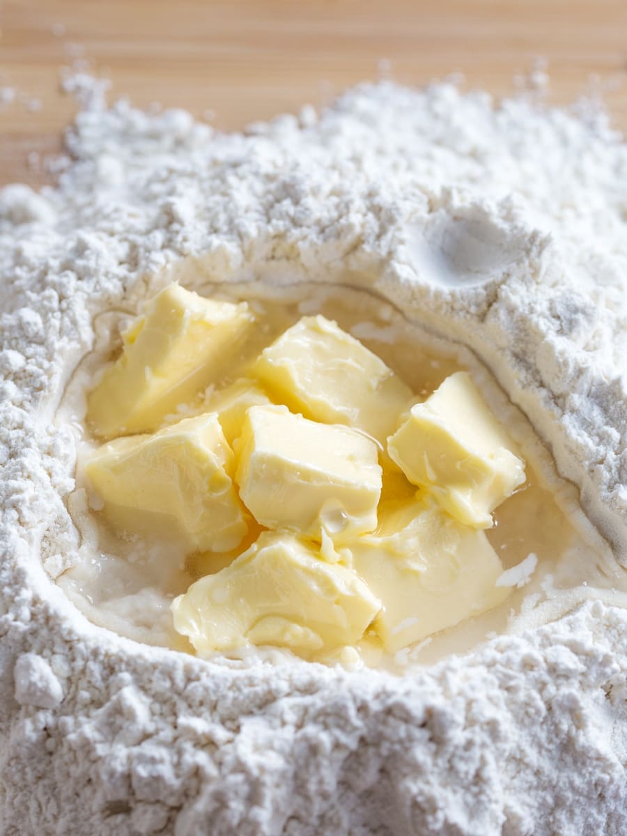 Mound of flour with cubed softened butter and water in the centre.