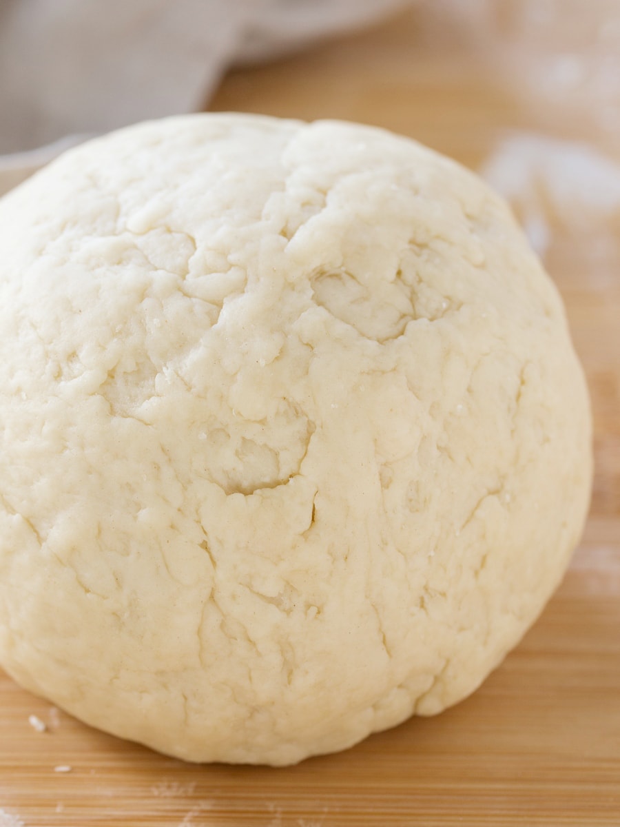 Empanada dough ball on a wooden surface.
