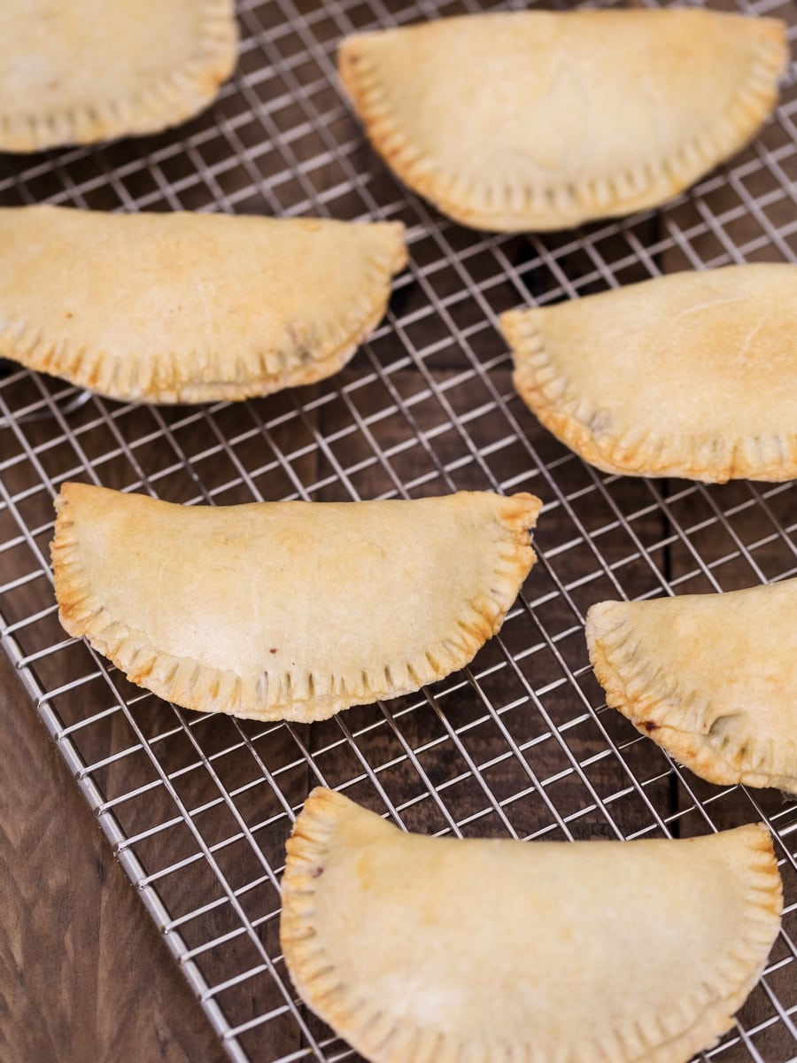Baked empanadas on a cooling rack.