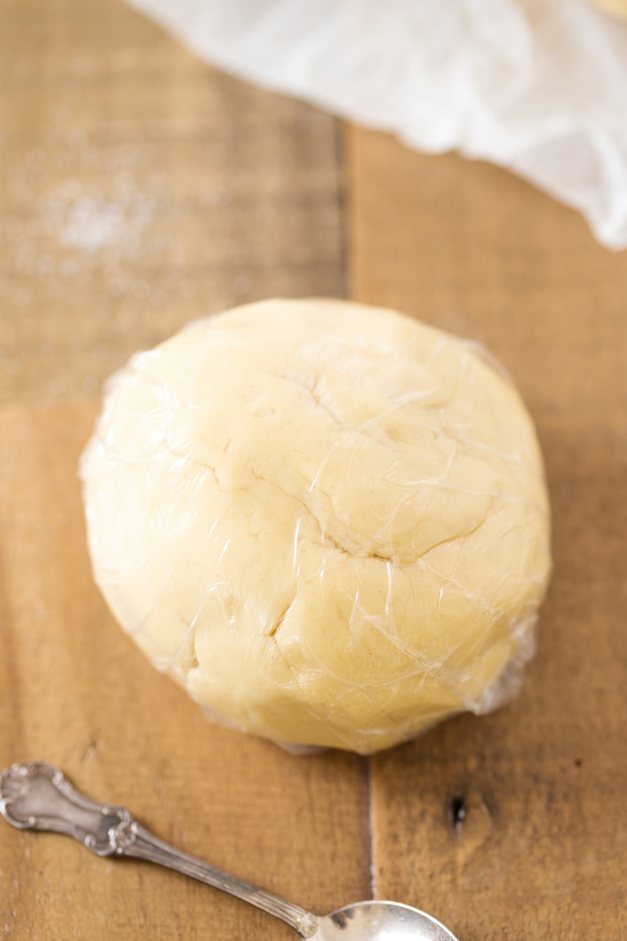 Ball of shortcrust psatry dough wrapped in plastic.