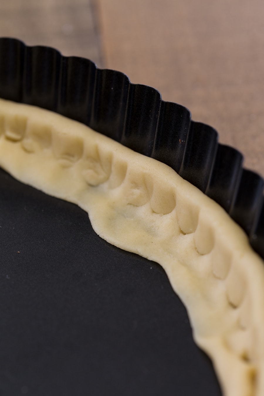 Pressing shortcrust pastry to tart pan sides with the handle of a fork.