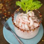 Italian shrimp cocktail served in a small glass over a blue plate.