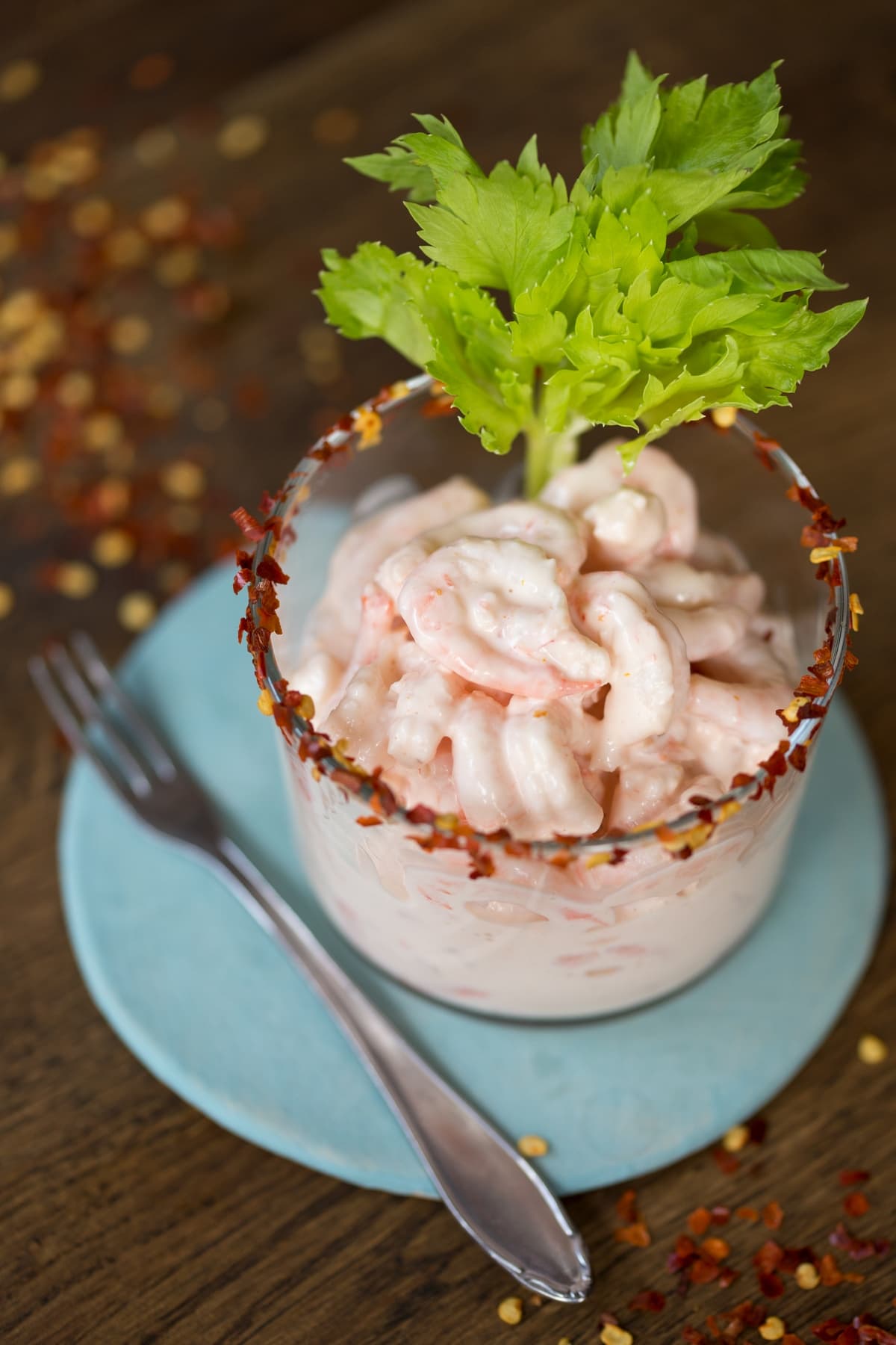 Italian shrimp cocktail served in a small glass over a blue plate.