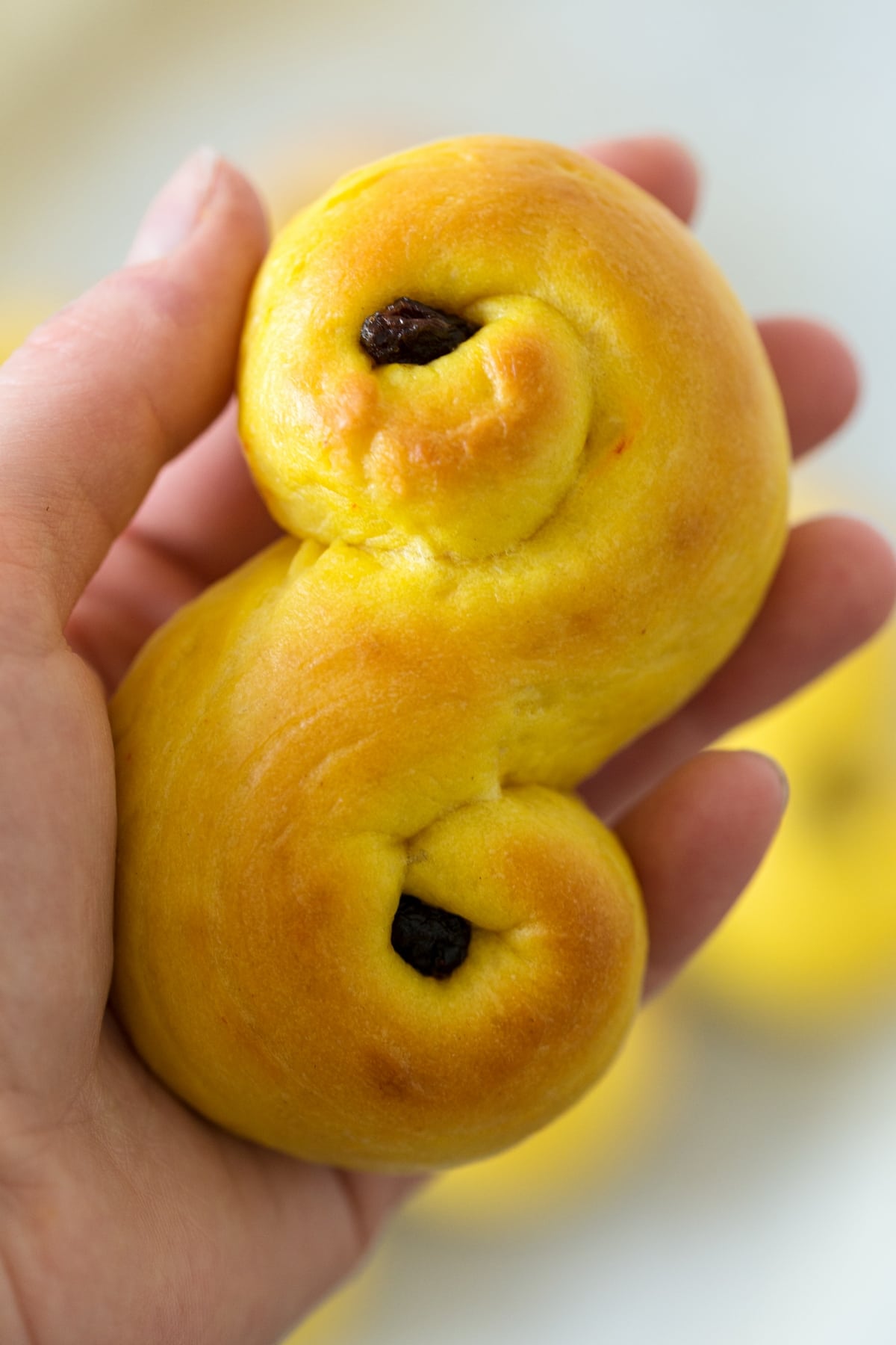 Hand holding a baked saffron bun.