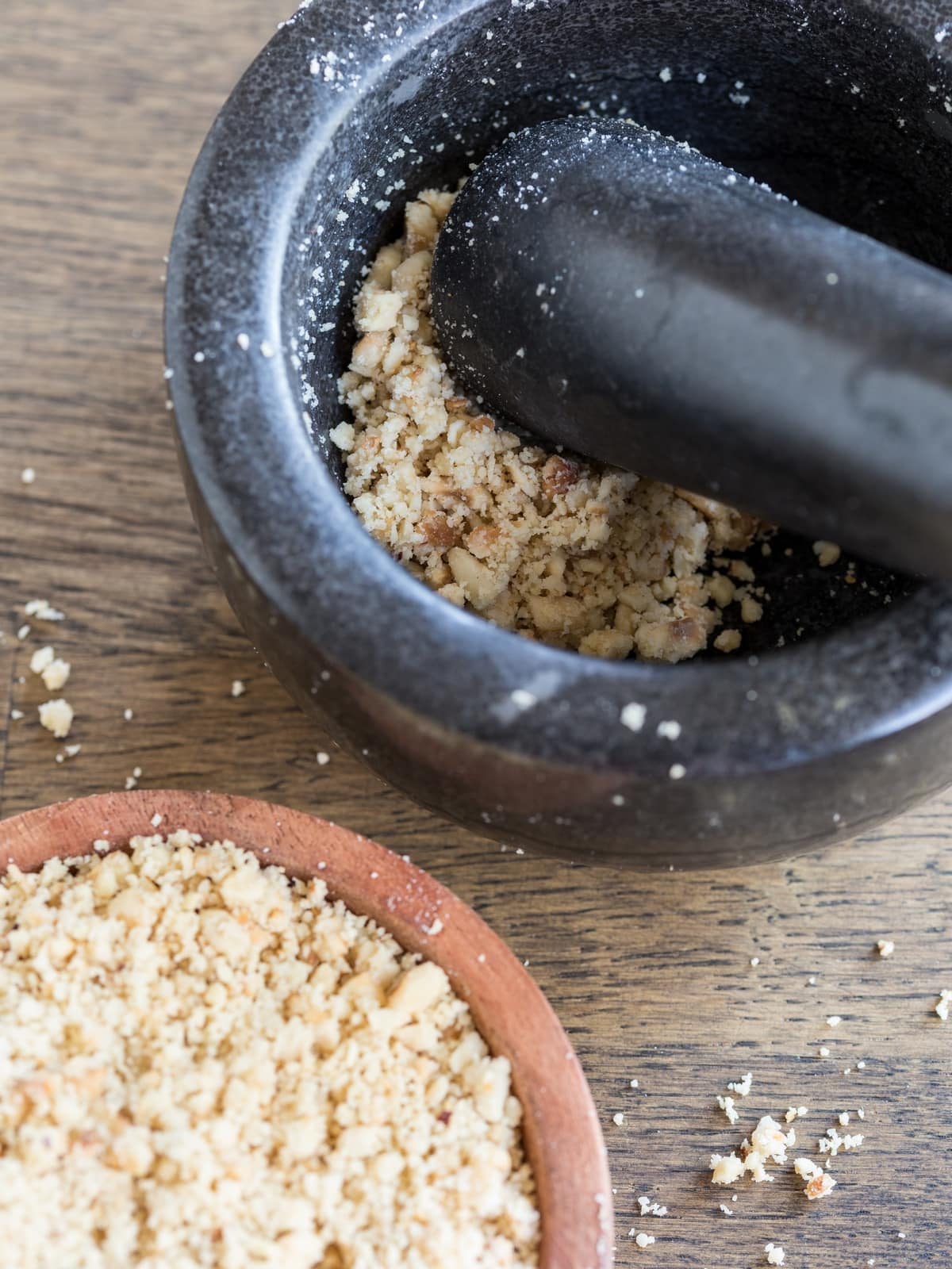 Ground hazelnuts in a mortar and in a wooden bowl.