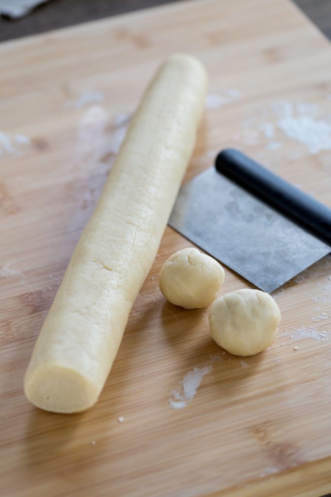 Dough cylinder with 2 small balls cut out.