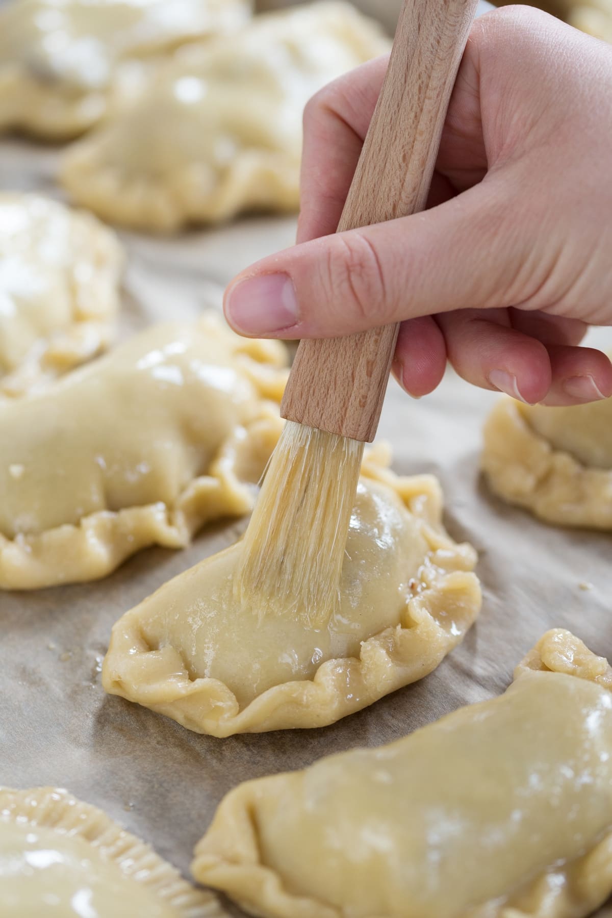 Brushing eggwash over homemade empanadas.