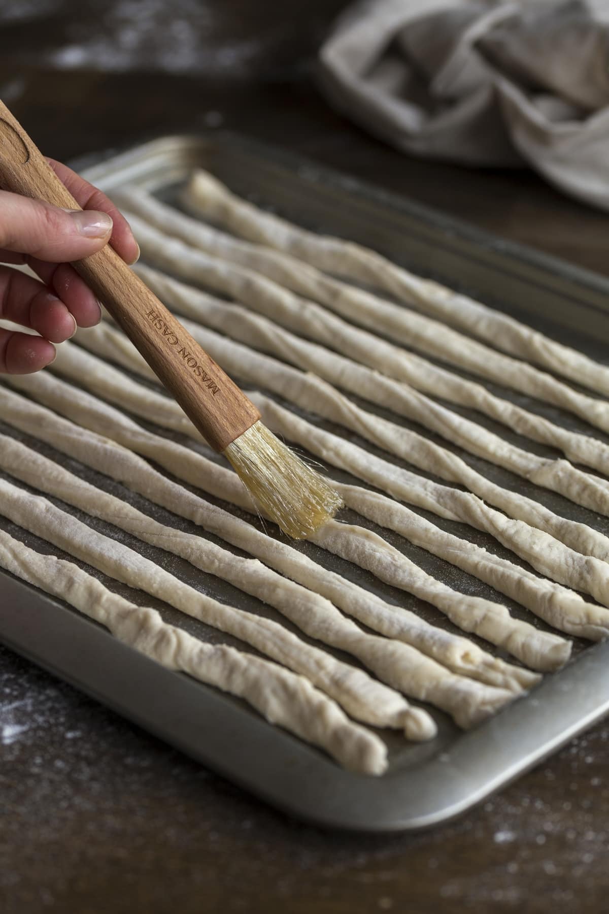 Adding melted lard to grissini surface.