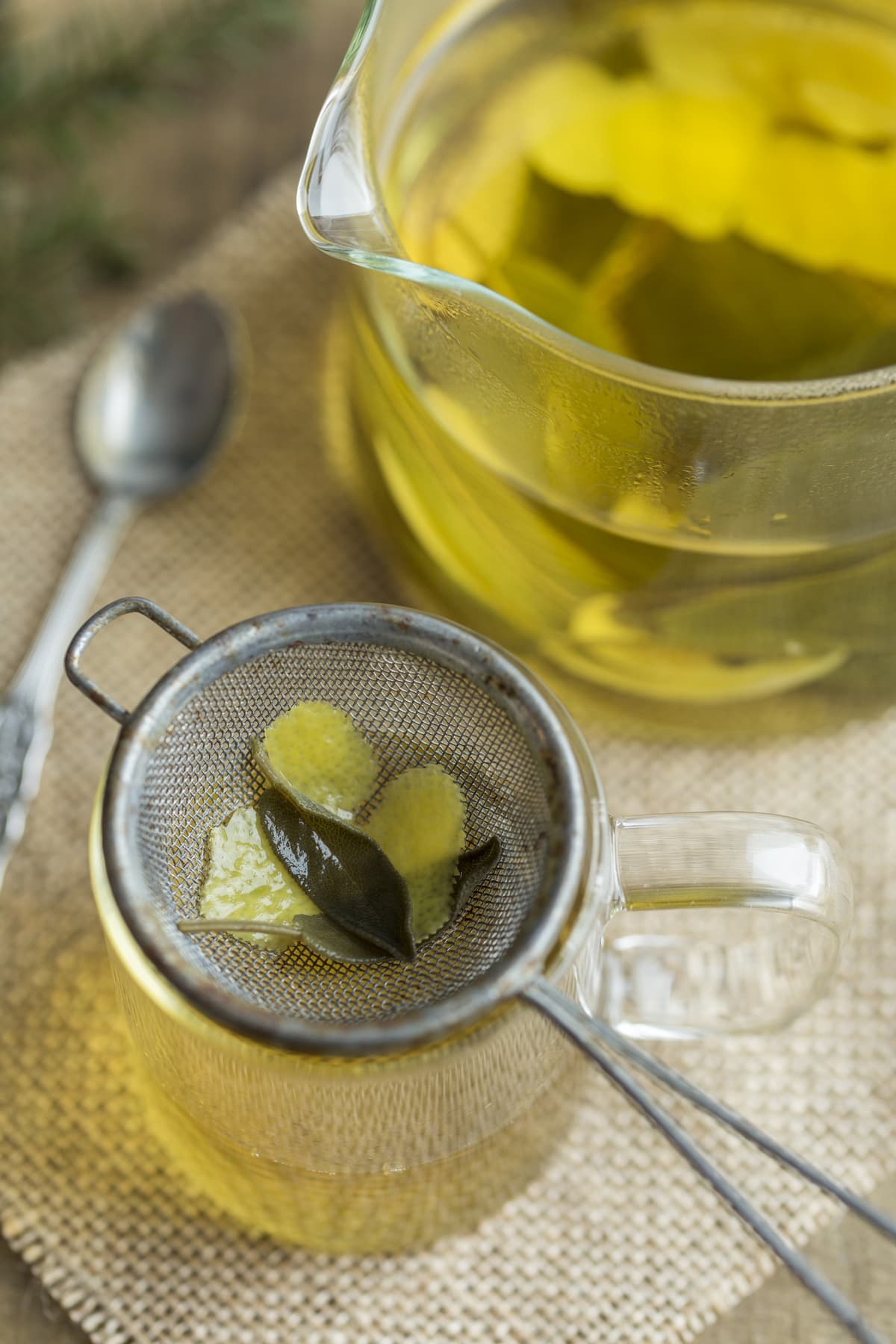 Pouring herbal infusion through a mesh sieve to retain debris.