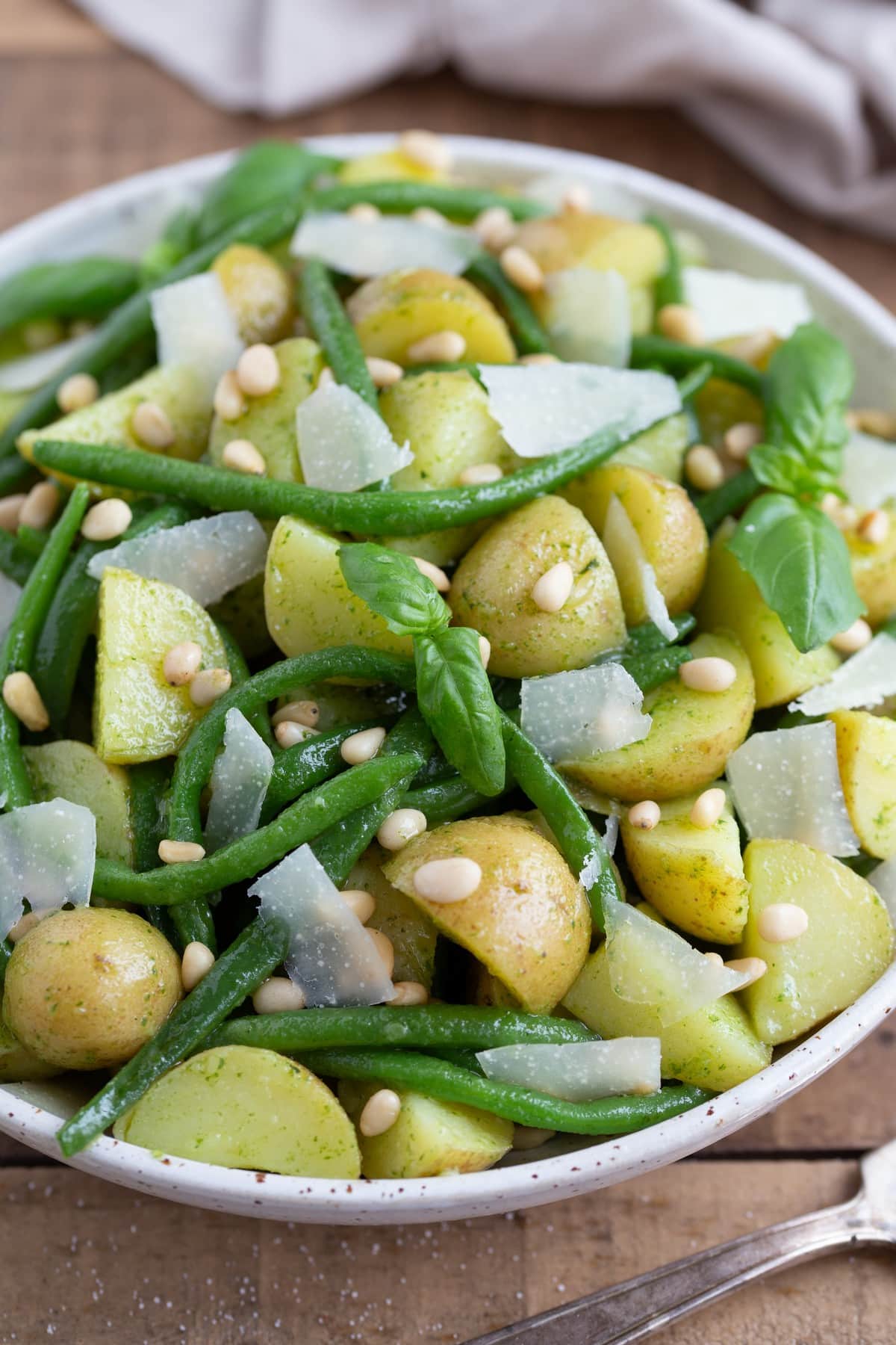 Pesto potato salad with green beans in a white serving bowl.