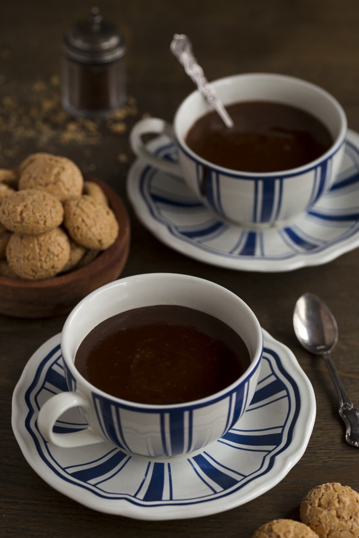Two cups of hot chocolate on a dark table.