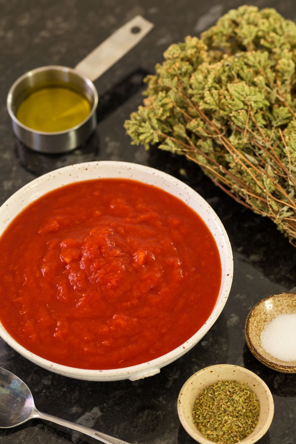 A bowl of crushed tomatoes surrounded by various condiments.